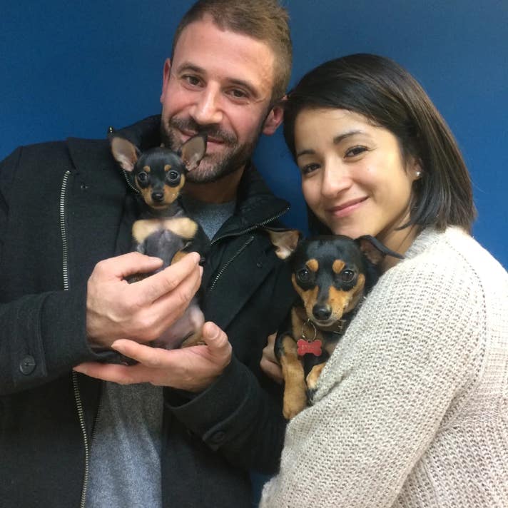 Chica y chico cada uno con un perro pinscher en brazos en la clínica veterinaria El Jardín.