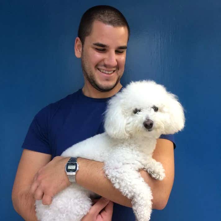 Chico con un perro caniche blanco en brazos en la clínica veterinaria El Jardín.