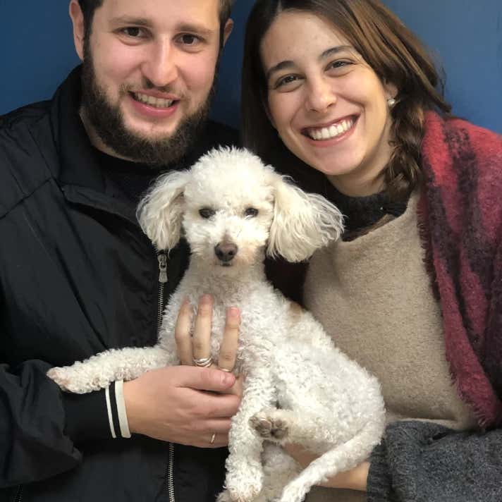 Chico y chica con un perro caniche blanco en brazos en la clínica veterinaria El Jardín.