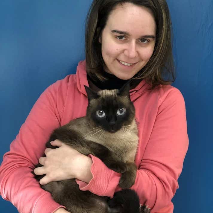 Chica con un gato siamés en brazos en la clínica veterinaria El Jardín.