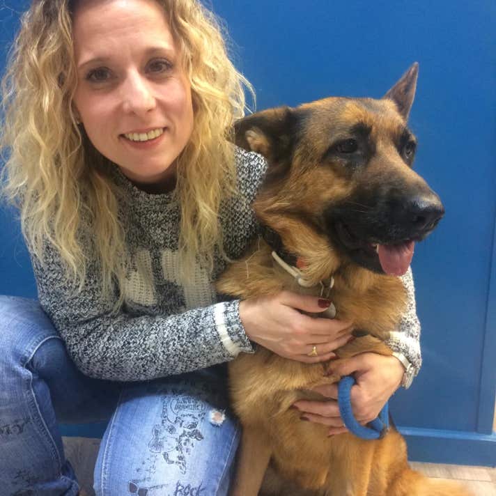 Chica con un perro pastor alemán agachados en el suelo en la clínica veterinaria El Jardín.